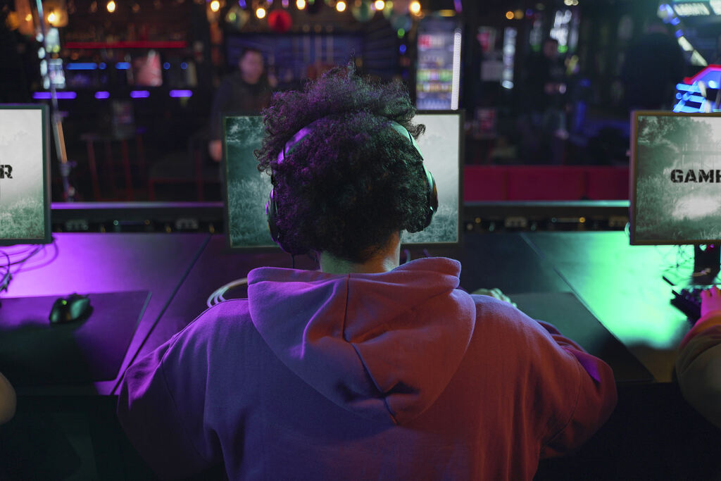  Aposta no cblol: Estande de jogos, um jovem de fente ao computador, de fundo muitas luzes coloridas