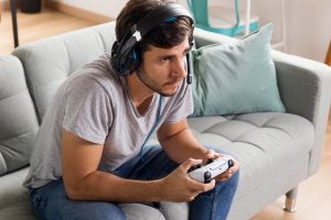 Pessoa jogando video-game segurando uma manete com fone de ouvido - Divulgação Freepik
